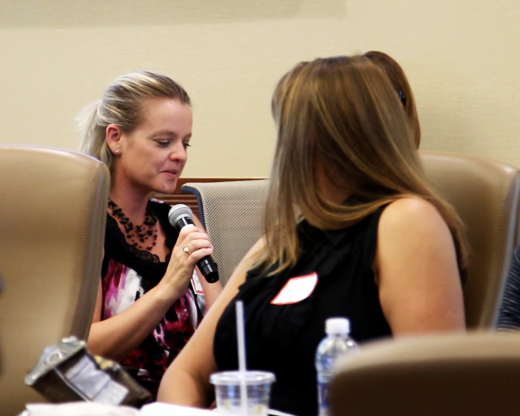 women sitting in a group, one holding a microphone